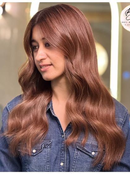 A smiling client enjoying her new deep, dimensional, and dripping-in-gloss rich brown hair.