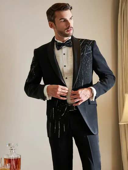 Adjusting the jacket, this shot gives a clear view of the intricate bead and sequin work on this modern black tuxedo. It's a piece designed for life's finest moments.