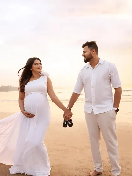 A sweet and classic beach pose. Holding hands and a tiny pair of baby shoes, this couple looks forward to their new beginning against a beautiful sunset.