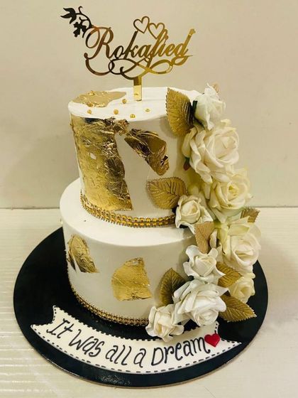 "It was all a Dream." A beautiful two-tiered white and gold cake for a "Rokafied" couple, featuring a cascade of white sugar roses and gold leaves.