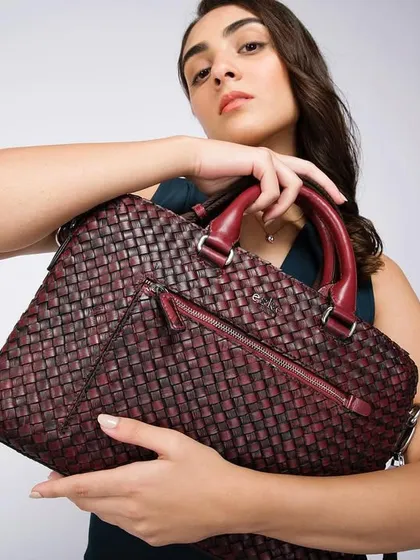Highlighting the intricate woven texture of an Eské Global laptop bag. This studio shot focuses on the product's detail and quality, with the model presenting it directly to the viewer.
