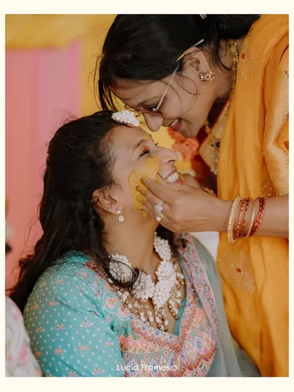 A mother's love captured as she applies Haldi to her daughter's face, a tender and emotional moment.