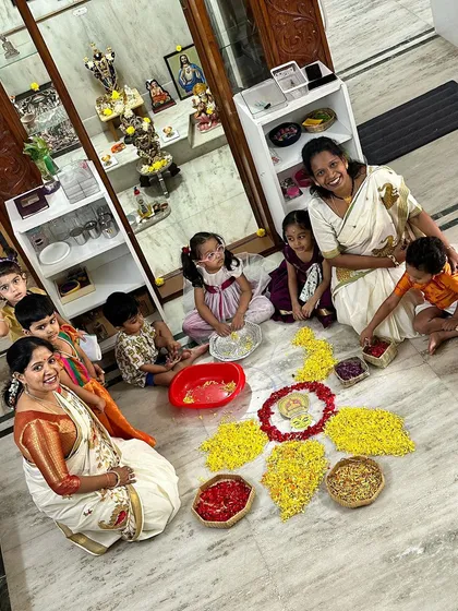 A beautiful moment of collaboration as children and teachers work together on the floor to create a flower rangoli.
