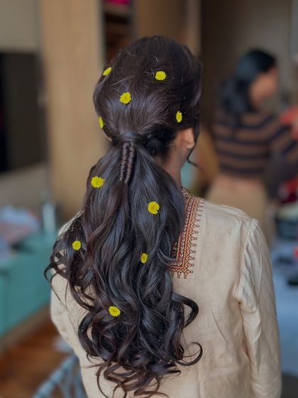 A playful ponytail for a haldi ceremony. I created a textured ponytail with soft waves and scattered small, fresh yellow flowers throughout for a sunny and cheerful look.