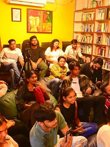 A full house for our open mic night, with the audience listening intently in our cozy, warmly lit library space.