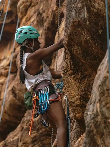 A climber fully equipped with a helmet, harness, and quickdraws for a day of sport climbing. We teach you how to use all this gear confidently.