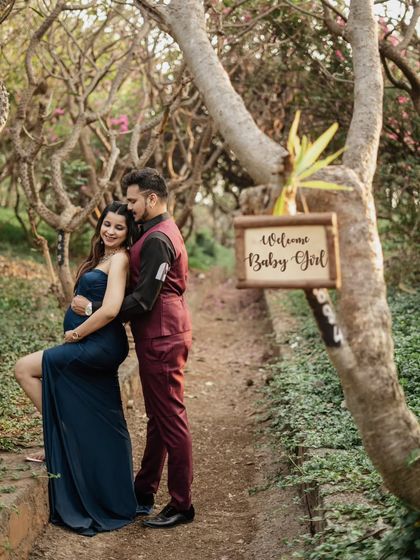 A subtle and sweet announcement during their outdoor shoot. The "Welcome Baby Girl" sign in the background adds a lovely personal touch to this romantic couple's portrait.