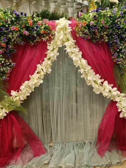 A vibrant and multi-layered ready-made backdrop, using different colored drapes and florals to create a rich and festive look.