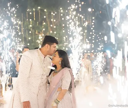 A cinematic shot of the groom kissing the bride's forehead amidst the sparklers.