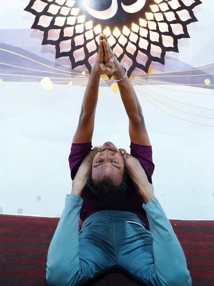 A deep forward bend with legs behind the head, a pose that requires immense flexibility and practice.