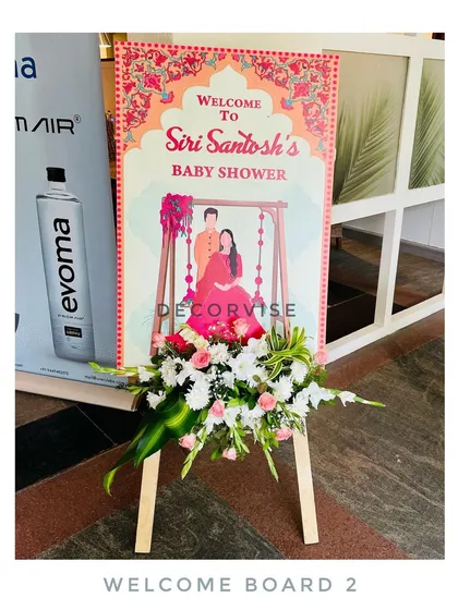 This is a personalized welcome board we designed for Siri and Santosh's baby shower. The custom illustration and elegant floral arrangement at the base create a warm and personal greeting for all the guests.