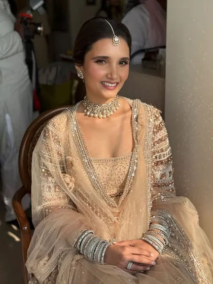 A seated portrait showing the full effect of her stunning pastel outfit. The makeup is kept clean and luminous, with a simple pearl choker and maang tikka completing the elegant look.
