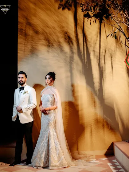 A stylish portrait of the couple, their elegant white and black outfits contrasting beautifully with the warm, ambient light.