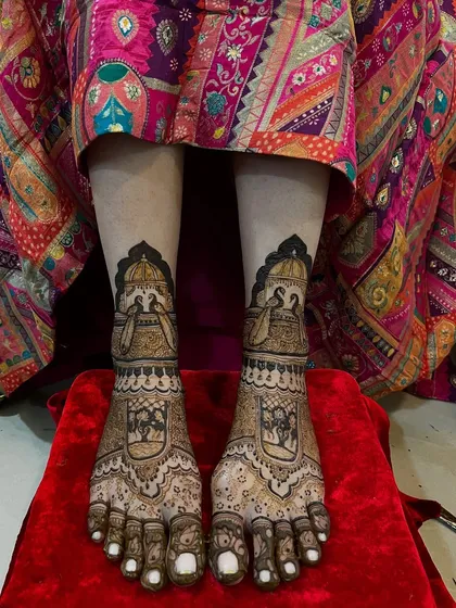 A beautiful bridal leg design featuring doli (palanquin) and peacock motifs. The pattern is intricate and tells a story, perfect for a bride's journey.