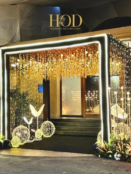 For a modern cocktail or sangeet night, I love creating high-energy, glamorous spaces. This entrance features a dramatic LED light frame, a ceiling of shimmering gold, and whimsical butterfly sculptures to set a vibrant and celebratory tone from the very first step.