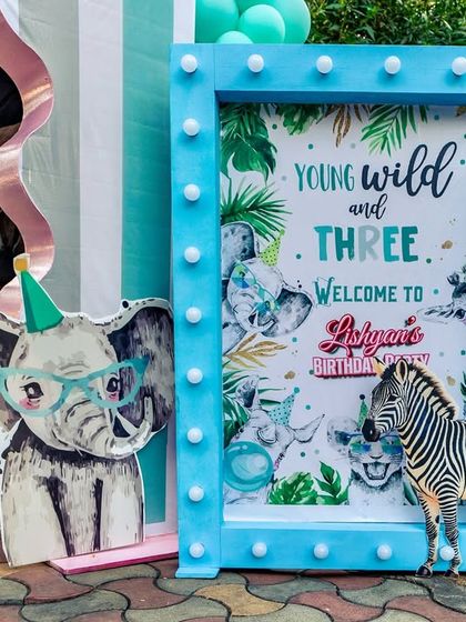 A "Young, Wild and Three" welcome sign with a cool elephant wearing glasses, setting a fun and quirky tone for the party.