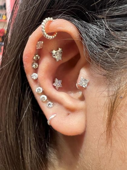 A mixed-metal ear stack that combines gold and silver tones. This look features a crescent moon hoop, star studs, and solitaire diamonds for a modern and dynamic style.