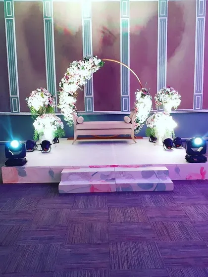 A minimalist stage setup I designed for an intimate wedding ceremony. The design features a simple wooden bench, a delicate semi-circular floral arch with white flowers, and strategic uplighting to create a romantic and elegant atmosphere.