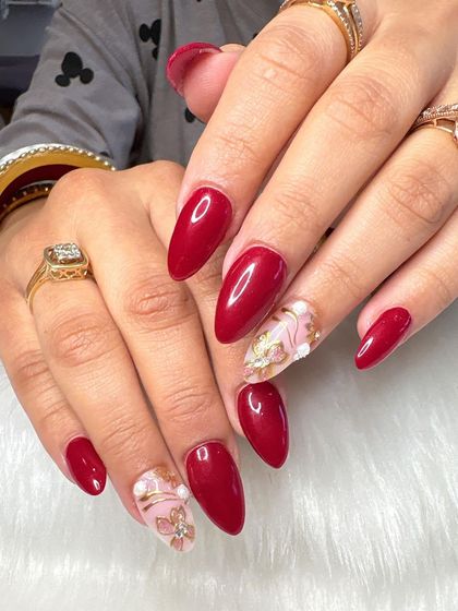 Feeling nail-tastic! A bold red manicure with accent nails featuring a marble effect and 3D gold floral charms.