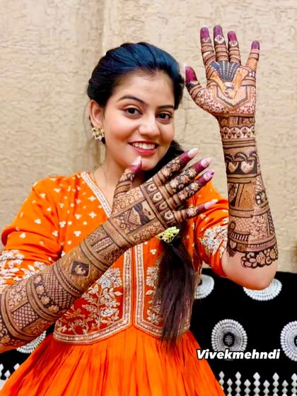 A happy bride proudly showing off her intricate full-arm mehndi. Her joy is what makes this art so special.