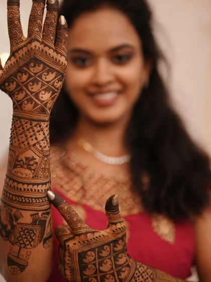A close-up shot focusing on the intricate details of the mehendi while capturing the client's happy expression.