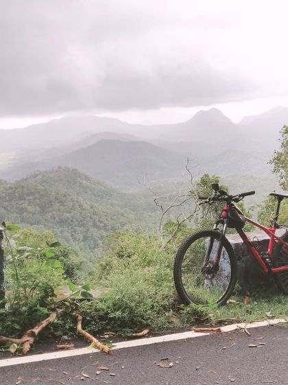 A mountain bike perfectly positioned to capture the moody, magnificent landscape of the Palani Hills. This showcases the kind of epic scenery and photo opportunities you'll find on our tours.