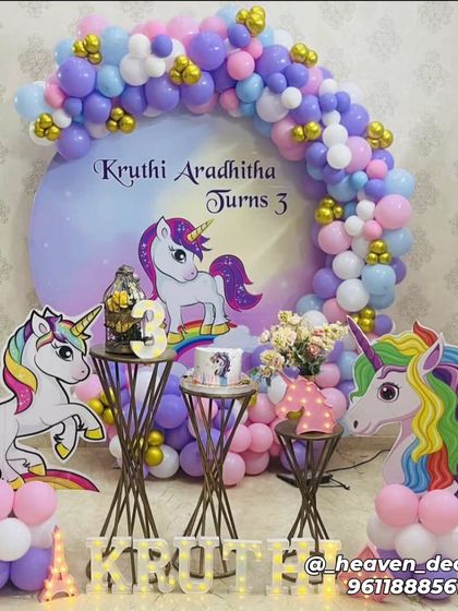 A classic unicorn party for a third birthday with a circular backdrop and multiple unicorn character cutouts. The setup is brought to life with a pastel balloon arch and elegant gold dessert stands.