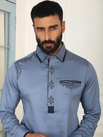 The soul of my craft lies in the details. This close-up of a sky-blue Pathani suit highlights the precise, geometric embroidery on the placket, shoulder, and pocket, a testament to the handcrafted elegance that defines every garment I create.