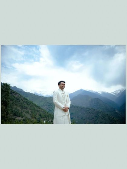 A stunning portrait of the groom against a backdrop of snow-capped mountains. This wide shot captures both the man and the majestic destination of his wedding.