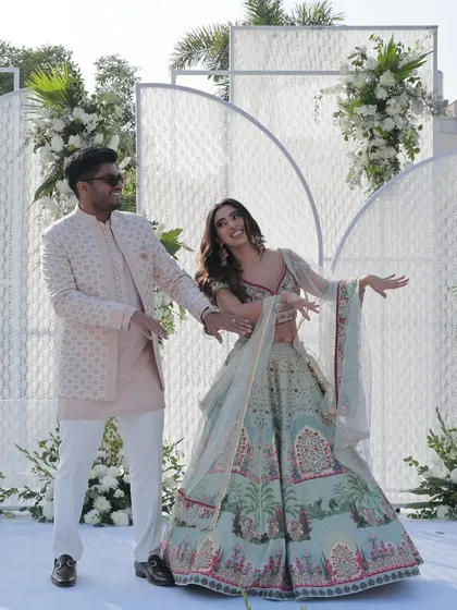 The couple shares a dance on their engagement day. The modern, all-white stage adorned with fresh flowers provides a stunning, minimalist backdrop.