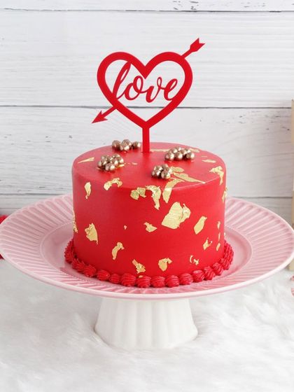 A bold red Valentine's cake with gold leaf accents, a luxurious and romantic dessert for your special someone.