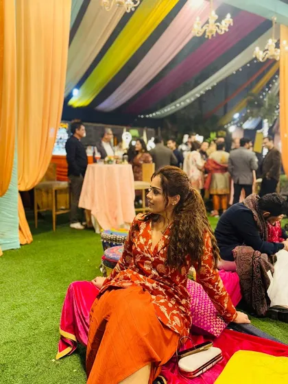 A different perspective of my Lohri outfit, showing the vibrant, festive atmosphere. The rust-orange color of the dhoti set stands out beautifully against the colorful decor.