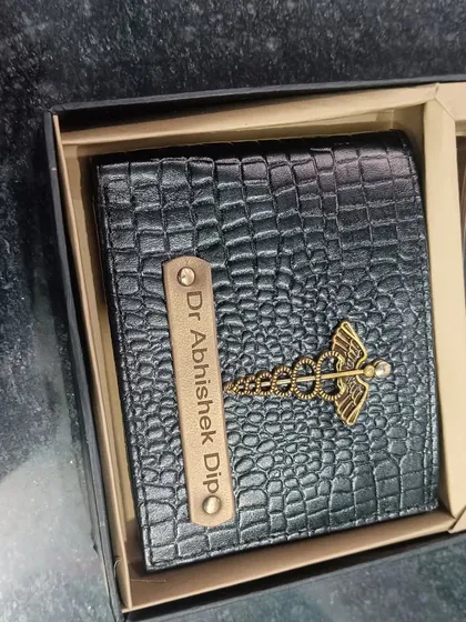 A personalized black crocodile leather wallet with a caduceus charm, specially designed for a doctor.