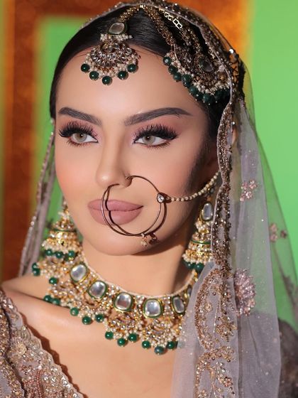 A beautiful bride adorned in a full green bridal set. This look features a detailed choker, matching earrings, a passa, maang tikka, and a delicate nath, showcasing a complete and cohesive style.