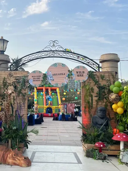 The outdoor venue was transformed into a vibrant jungle with colorful overhead draping, festive buntings, and an expansive play area, ensuring an immersive experience for all the young guests.