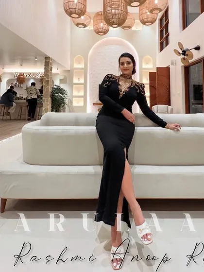 A client looking absolutely glamorous in a custom black gown for her birthday. The gown features a thigh-high slit and stunning gold embroidery on the shoulders and neckline.