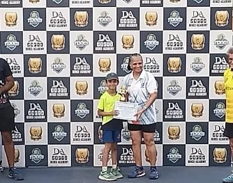 A young player from our academy receives her U8 aptitude title trophy at the Deuce Open Tennis Tournament in Noida. Her smile shows the confidence gained from competitive play.
