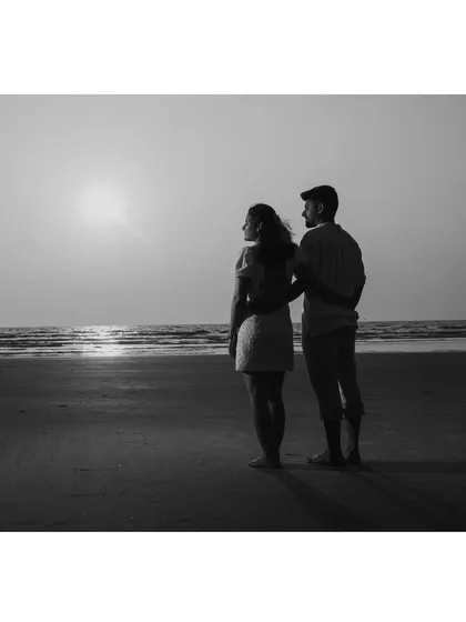 A classic black and white portrait of the couple looking out at the sunset. It's a timeless and contemplative image.