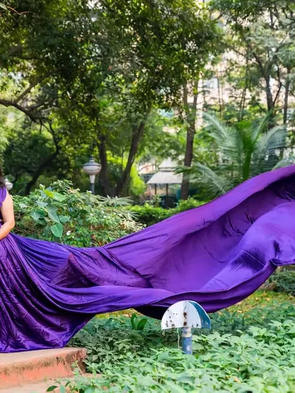 A dramatic, wide-angle shot showcasing the incredible train of this purple gown, flowing out across the green lawn.