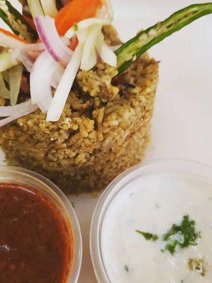 This is my Thuppangadi Chicken Biriyani, carefully plated and topped with a fresh salad of julienned vegetables. Every serving comes with my signature spicy salan and creamy homemade raita to balance the flavors.