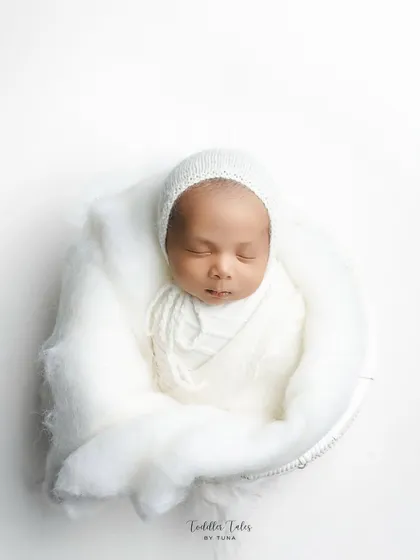 Wrapped in pure white, this 18-day-old newborn rests peacefully. My minimalist newborn photography focuses on their serene beauty and delicate features, creating a clean and timeless portrait.