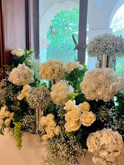 A close-up of a lush floral arrangement featuring a mix of white roses, hydrangeas, and baby's breath. The density and variety of flowers create a rich texture that is both classic and breathtaking.