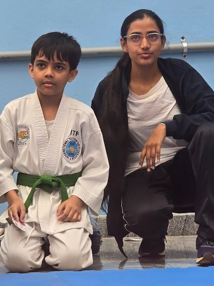 A quiet moment of mentorship with a young green belt student during a competition.