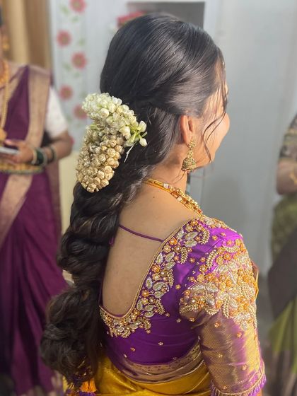 A close-up from the back, focusing on the fresh jasmine flowers and the intricate braiding.