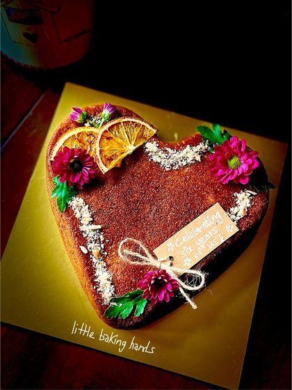 Another angle of the heart-shaped orange gulkand cake, showing off its beautiful decoration of edible flowers and dried orange.