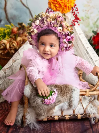 A little flower fairy in her enchanted woodland seat. The oversized floral bonnet is such a whimsical touch for this nature-inspired theme.