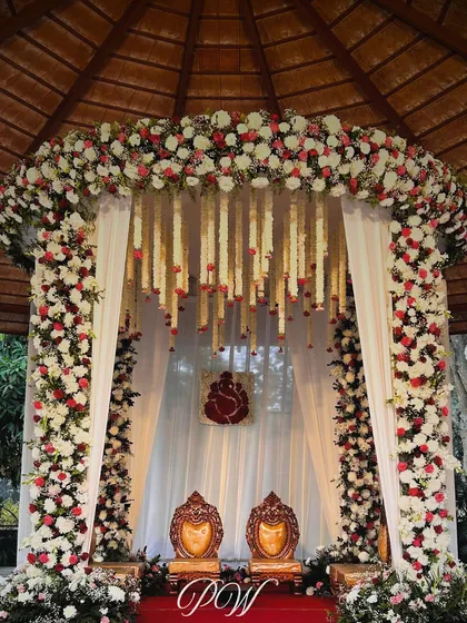 A beautiful floral mandap designed for an intimate wedding ceremony. The arch of white and red roses, paired with hanging floral strings, created a perfect frame for the couple's sacred vows.