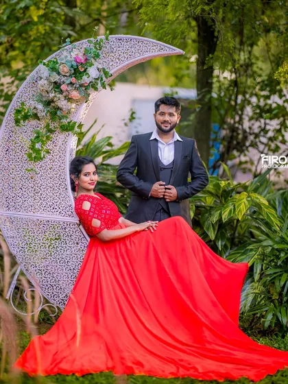 I love using whimsical props to add a touch of fantasy to your shoot. Here, the couple is framed by a beautiful crescent moon seat, with the mom-to-be's vibrant red gown creating a stunning visual contrast against the lush green garden.