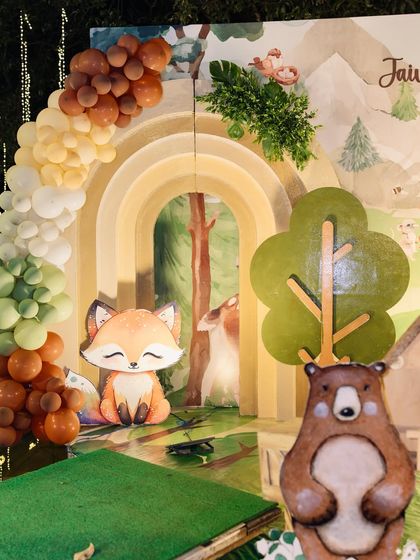 A colorful woodland setup for Jaivik Viraj's birthday. This scene features a rainbow-shaped balloon arch, friendly bear and fox cutouts, and a tree prop, creating a bright and cheerful forest adventure.