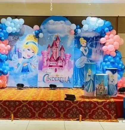 A grand stage setup for a Cinderella-themed birthday party, with three large backdrops featuring the princess and her castle.